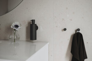 Home Black soap dispenser and hooks in mat black on beige tiles.